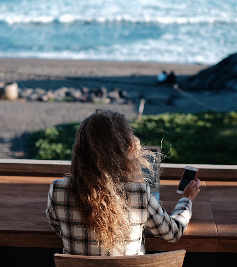 donna utilizza pc e cellulare al mare
