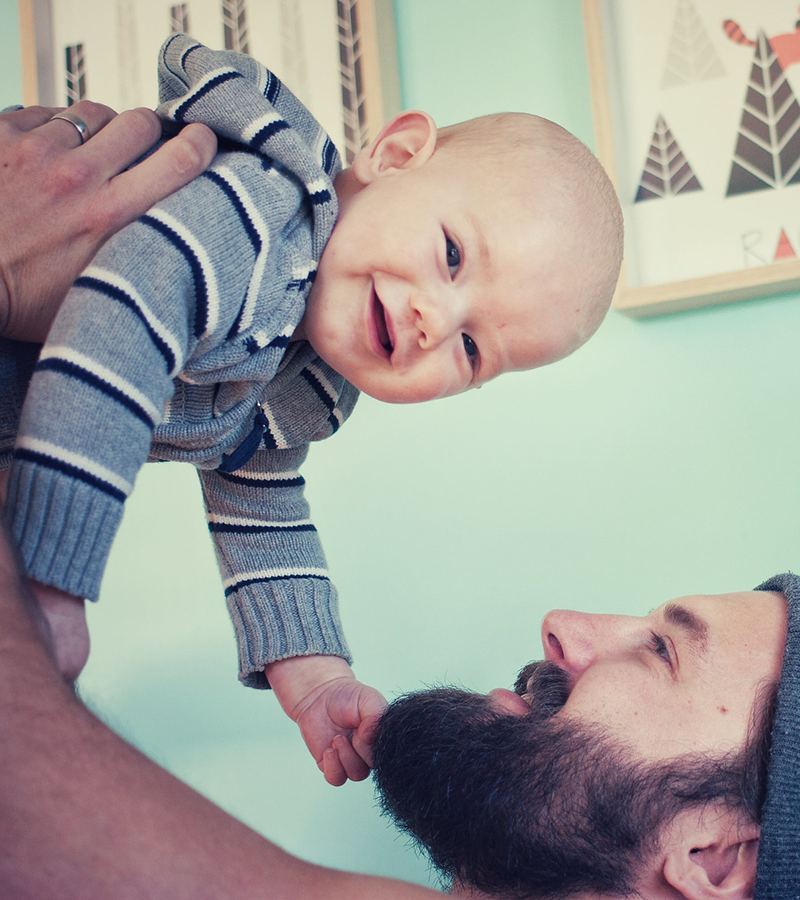 padre solleva tra le braccia suo figlio piccolo