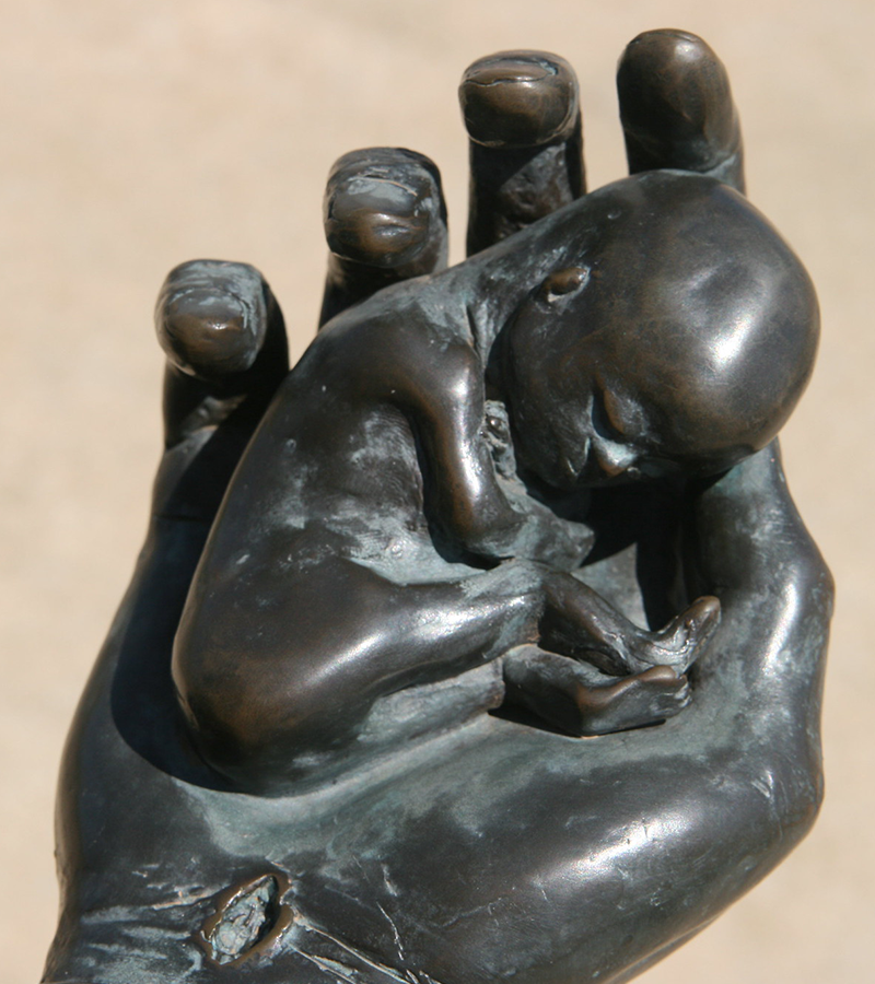 Scultura di una mano che sorregge un feto